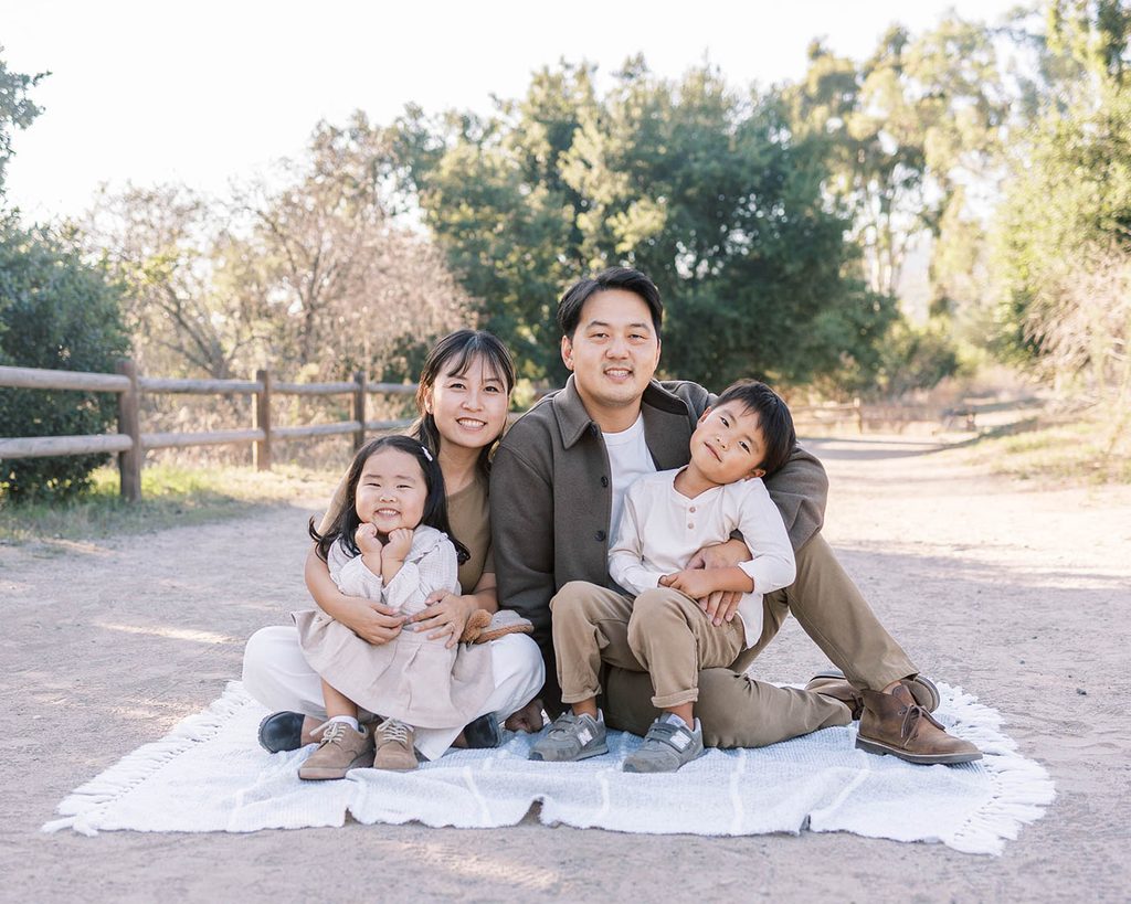 Asian family sitting and smiling on blanket during a family photoshoot