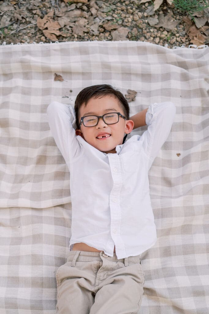 Boy smiling on gingham blanket in Irvine park