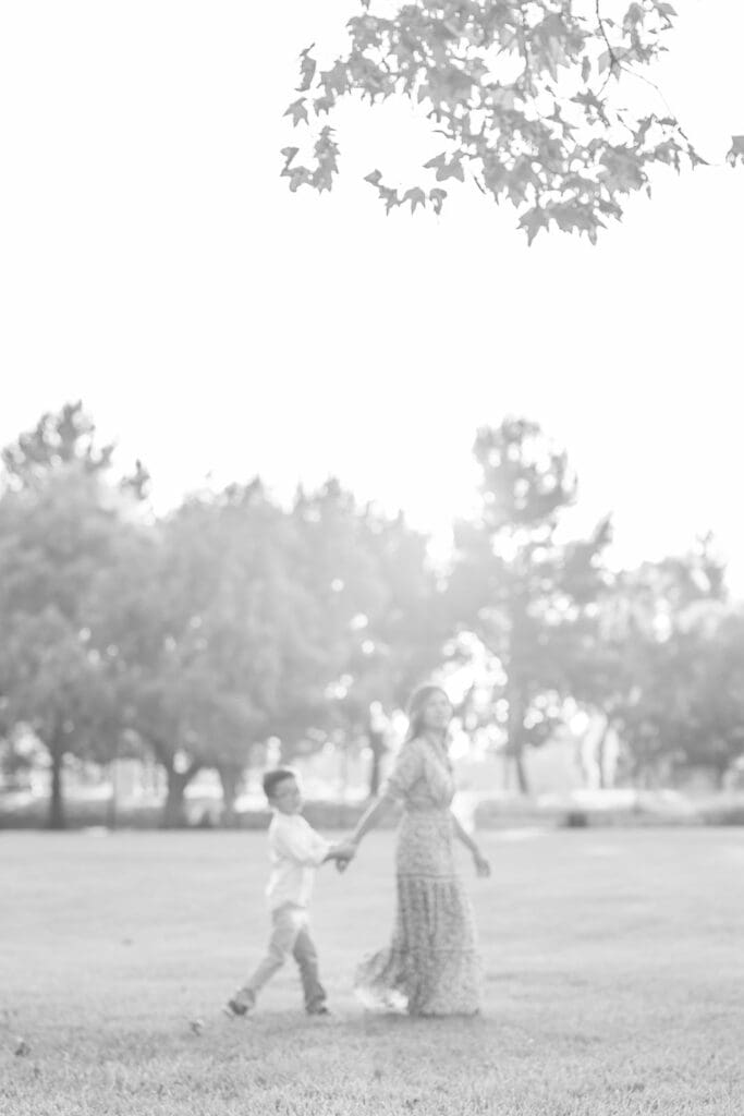 dreamy black and white photo of mom leading son during outdoor photoshoot location in Orange County