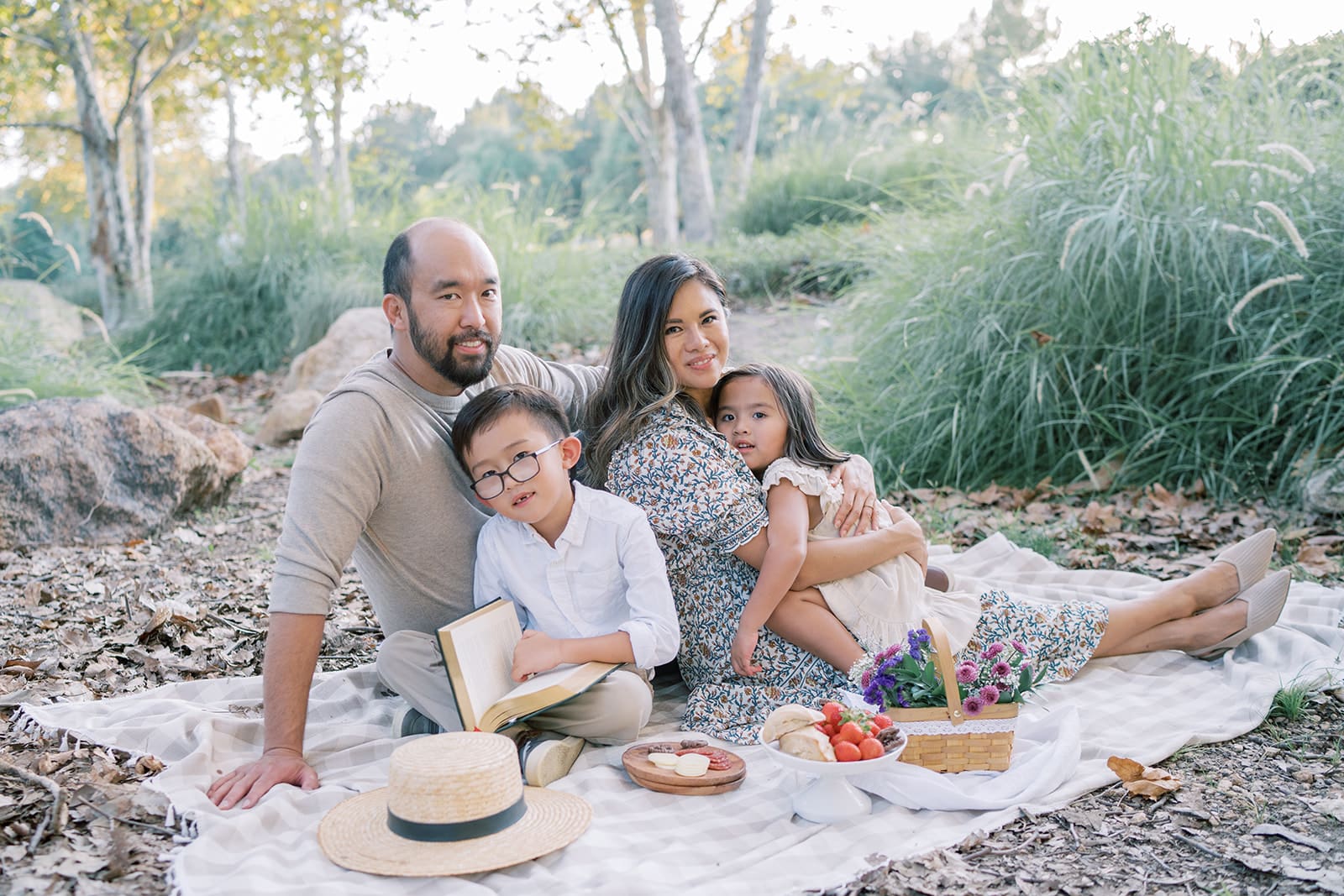 family sitting and smiling on picnic blanket in Orange County