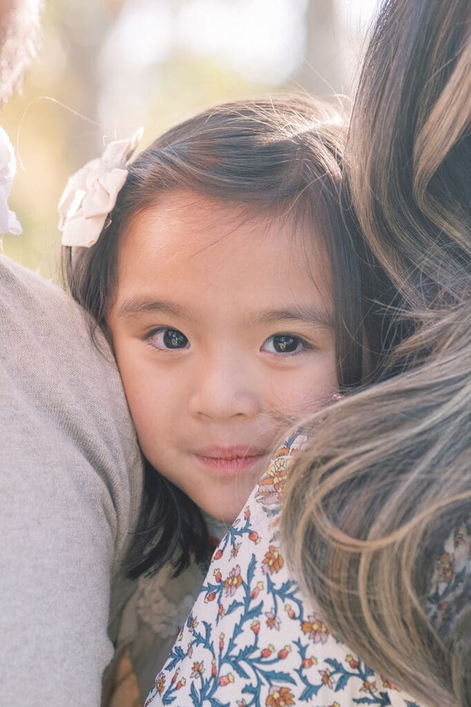 girl smiling between parents in outdoor photoshoot location in orange county