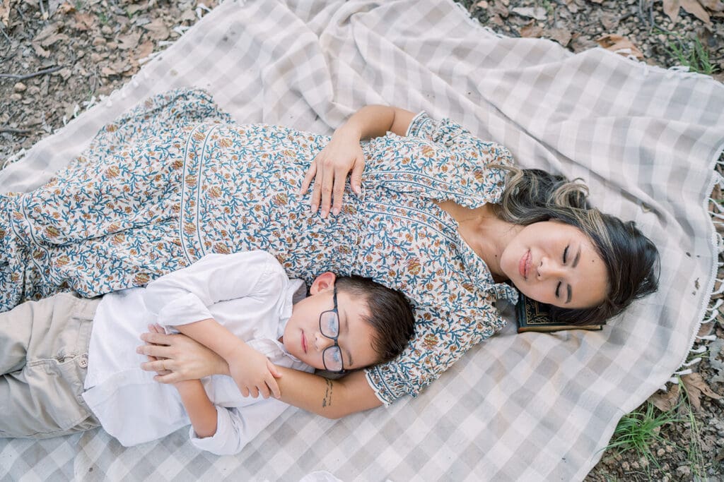 mom and child sleeping on picnic blanket 